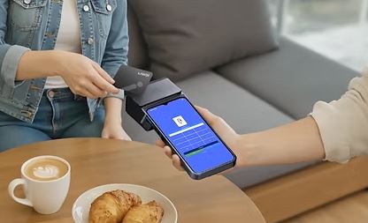 Guest tapping a card on a Diner Daddy handheld POS at a café table